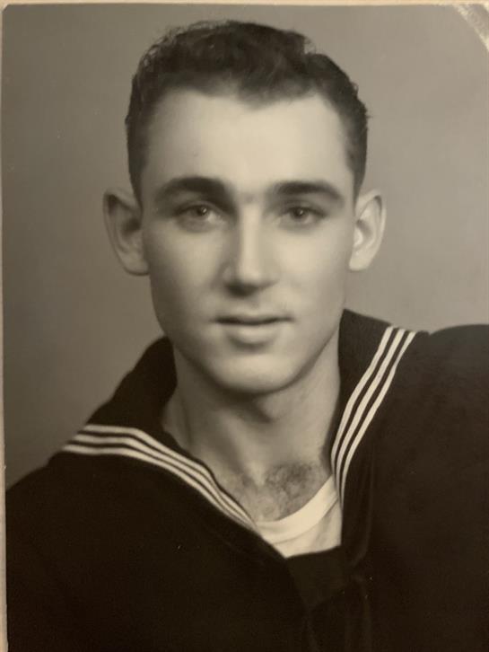 Young sailor proudly poses in uniform, displaying his youth and commitment to naval service.