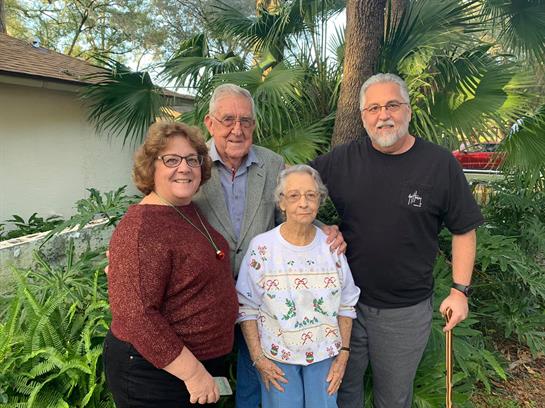 Four family members gather in a vibrant garden, enjoying each other's company and comfort.