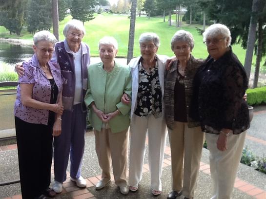 Elderly women gather together outside, enjoying each other's company in a lush green park.