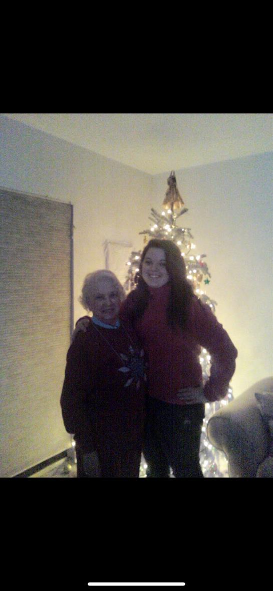 Two individuals pose together joyfully in a cozy room decorated for Christmas.