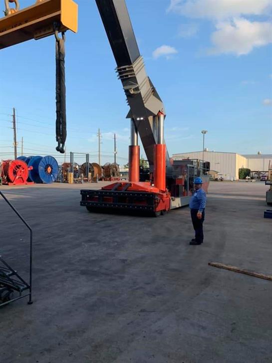 A worker supervises a crane lifting cargo in a busy construction area during sunset hours.