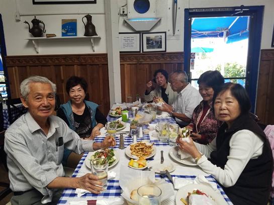 A group of friends sits around a table enjoying various dishes and drinks in a warm atmosphere.