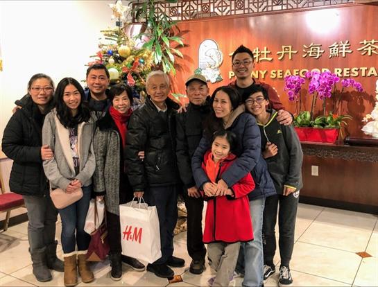 A large family poses together at a lively seafood restaurant, celebrating the holidays.