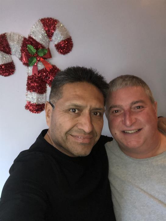 Two friends pose for a cheerful selfie in front of festive holiday decorations.
