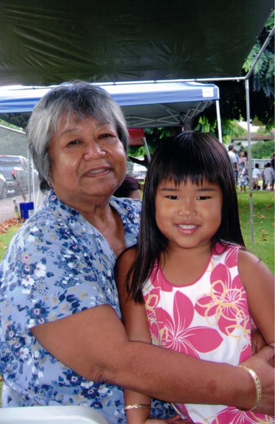 A grandmother and her granddaughter enjoy a joyful moment at a summer community gathering outdoors.