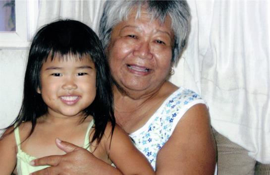 A grandmother smiles, holding her granddaughter close in a cozy family moment.