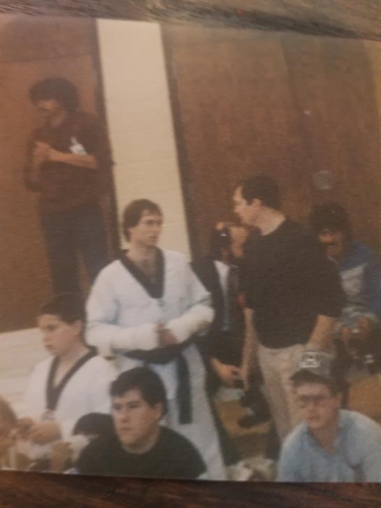 A group gathers to watch martial arts practice, featuring participants in uniforms and spectators.