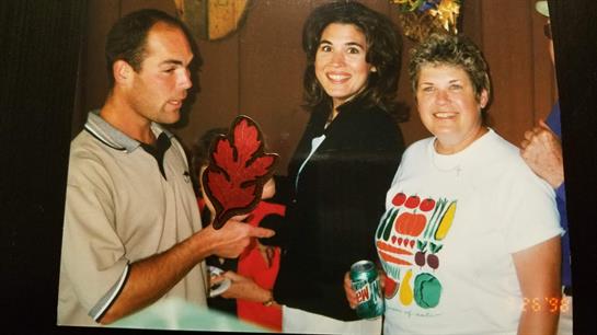Group of friends smiling and enjoying themselves while holding a decorative item and drinks.
