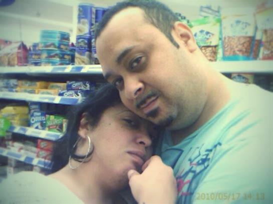 A couple shares a tender moment in a grocery store, surrounded by various products.