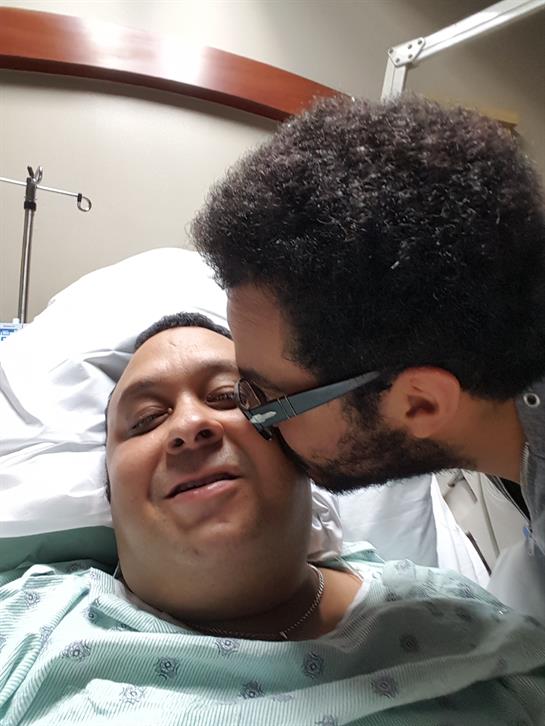 A close family interaction occurs in a hospital room as one person comforts another.