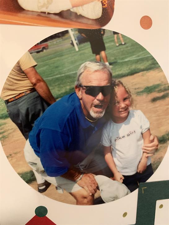 A smiling grandfather and his granddaughter enjoy a bright day together at the park.