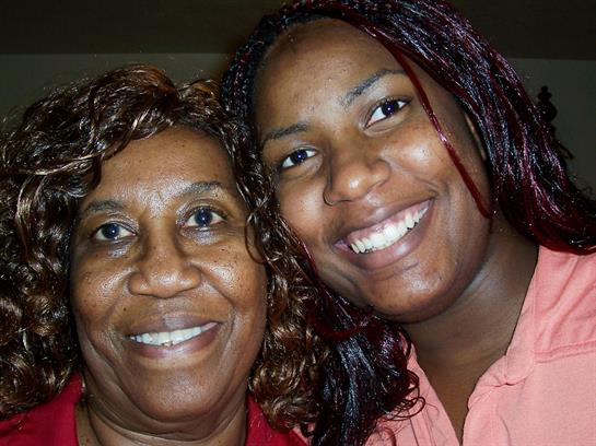 Two women share a joyful moment indoors, smiling happily while showcasing their bond and warmth.