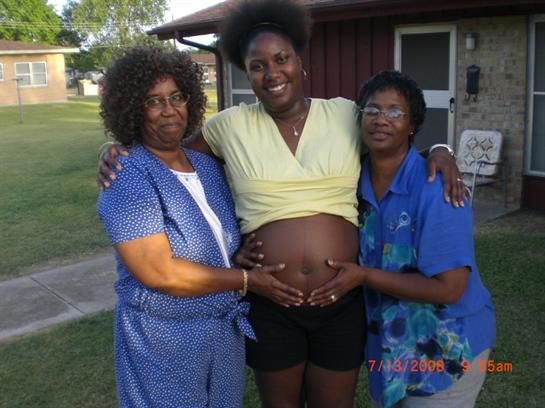 Friends and family happily celebrate a pregnancy milestone at a gathering outside a house.