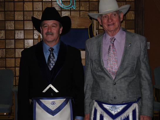 Two men dressed in suits and cowboy hats stand together at a social event, showcasing their attire.