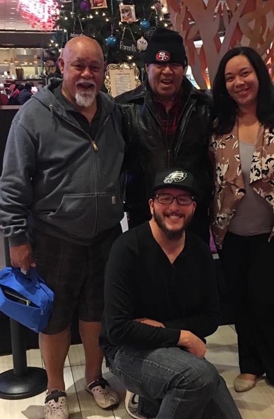 Four friends smile together, enjoying a light moment indoors at a casual gathering.