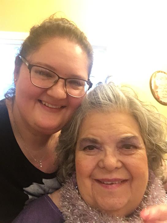 Two women pose closely together, smiling joyfully while sharing a special moment at home.