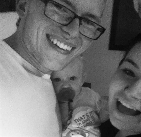 Happy family sharing a joyful moment while holding their baby at home during the evening hours.