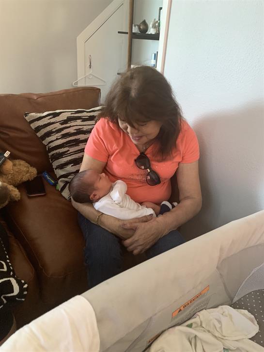 A grandmother and her newborn grandchild enjoy a tender moment together at home.