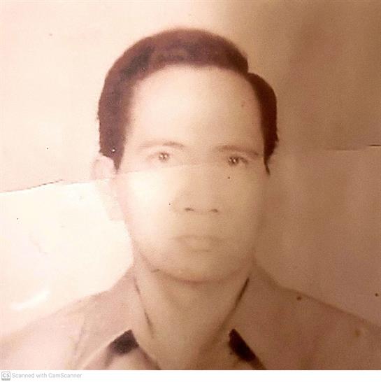A man in a collared shirt poses seriously against a faded background.