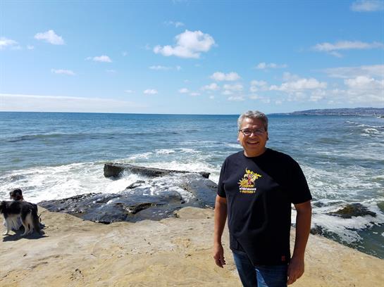 Man enjoys a sunny day at the beach, surrounded by ocean waves and clear blue skies.