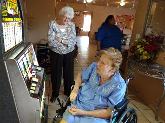 Two seniors engage at a slot machine, sharing moments of joy and laughter in a recreation center.