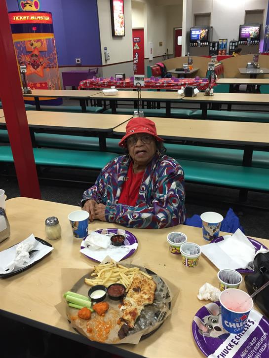 A woman sits at a table enjoying a diverse meal in a brightly colored community dining area.