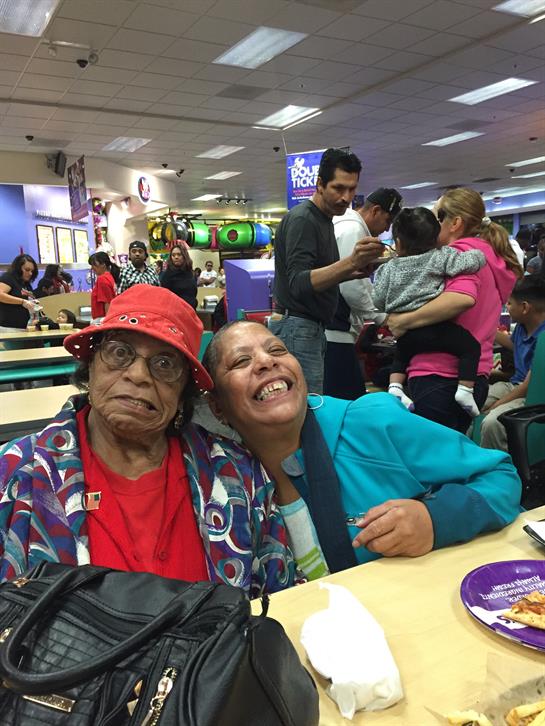 Two women enjoy a joyful moment together in a vibrant indoor play area filled with families.