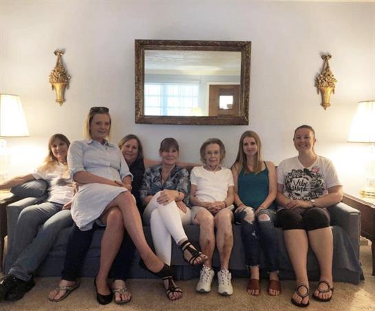 A group of seven individuals seated comfortably on a couch, enjoying quality time together.