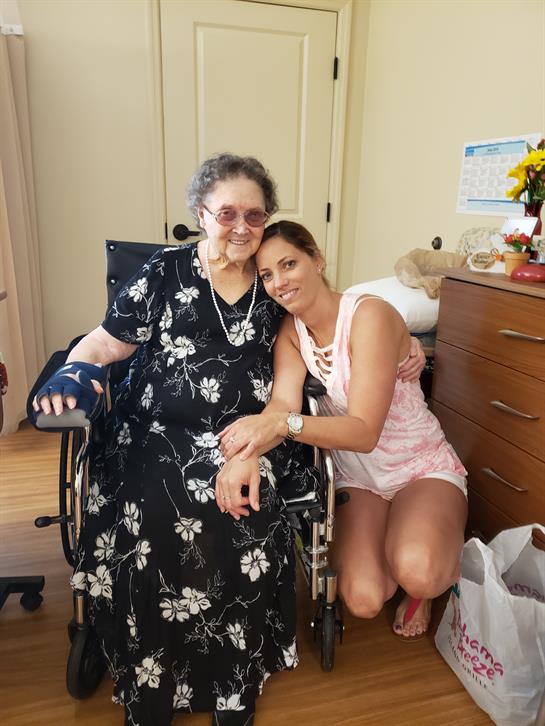 A young woman shares a joyful embrace with an older woman in a warm, inviting room.