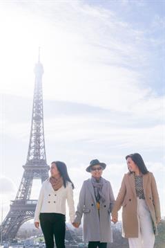 Friends enjoy a walk near the Eiffel Tower, soaking up the sun on a clear day in Paris.