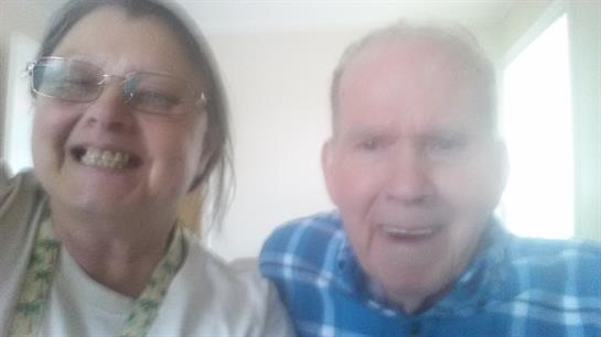 A happy older couple smiles widely, sharing a joyful moment together at home.