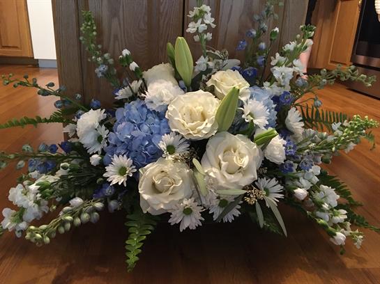 A vibrant floral display showcases white and blue flowers arranged elegantly in a rustic setting.