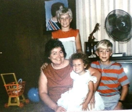 A joyful family moment with children and their grandmother smiling together in a cozy living room.