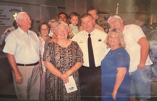 A large family poses together with a sheriff in uniform, celebrating a special occasion.