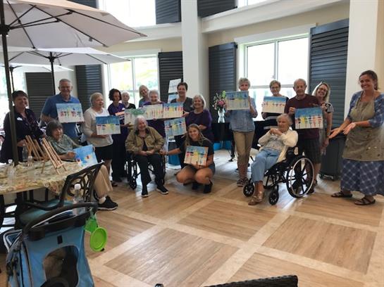 Seniors engage in a creative art session at a community center, showcasing their artwork together.