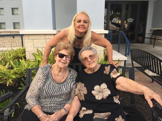 Three friends smile and pose for a photo on a sunny day, enjoying each other's company.
