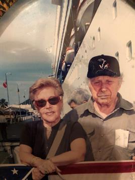 Two older adults pose together by a marina, sharing smiles and enjoying their time outdoors.