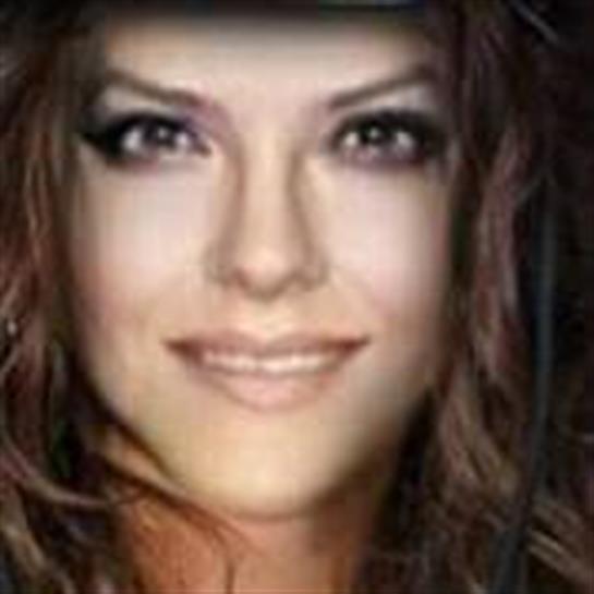 Woman with long wavy hair smiles warmly, radiating confidence in a relaxed vibe.