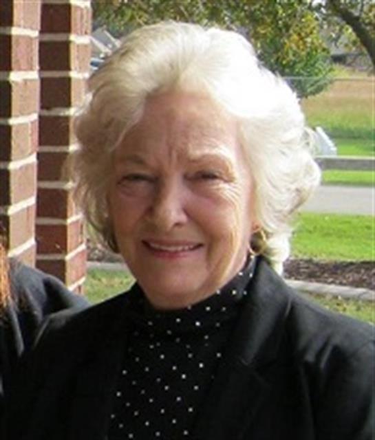 Joyful senior woman with light hair poses happily outdoors at a community event.