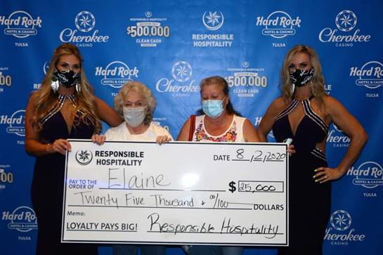 Four women proudly pose with a large check for twenty-five thousand dollars at a hospitality event.
