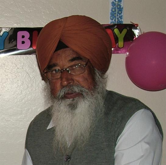 An elderly man in traditional attire celebrates his birthday amid cheerful decorations.