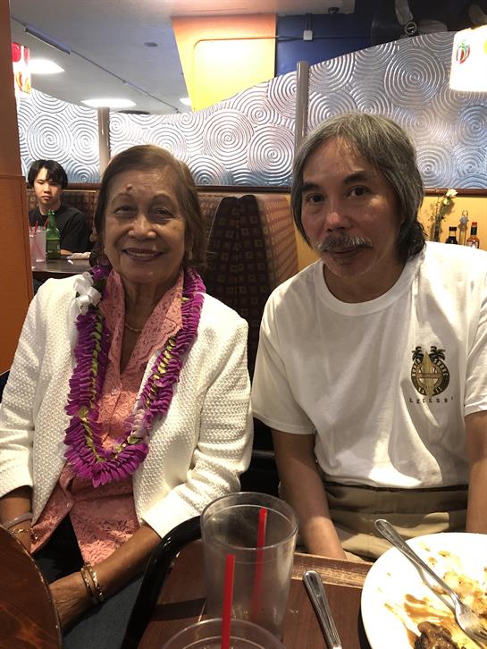 Two smiling relatives pose together in a restaurant, showcasing happiness and connection.