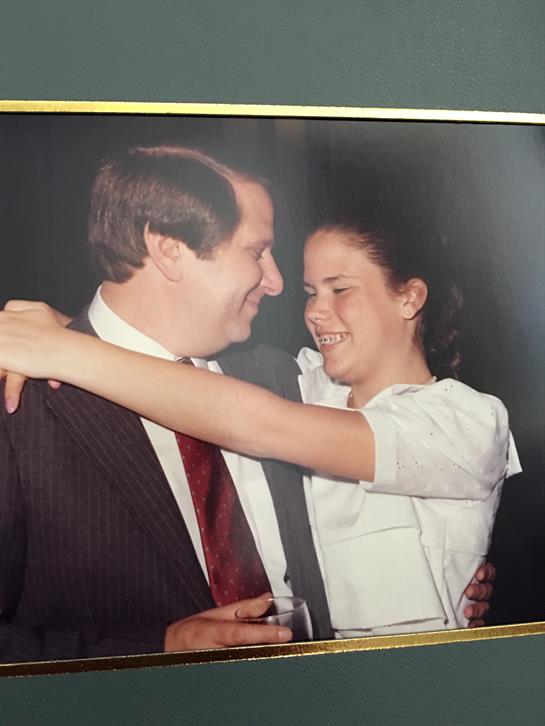 A couple is embracing and smiling at each other, enjoying a special moment at an indoor event.