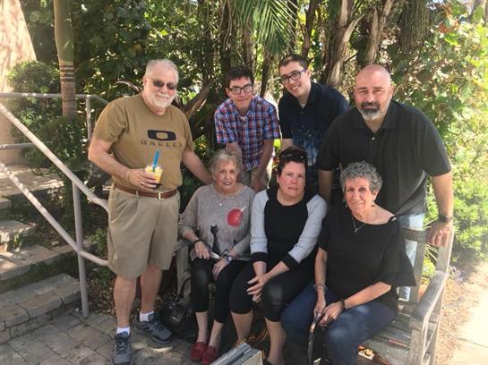 Group of friends and family smiling and posing for a picture in a lush garden setting.