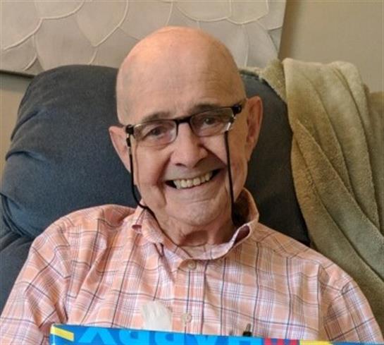 Senior man is happily smiling in a comfortable living room, wearing glasses and enjoying his day.