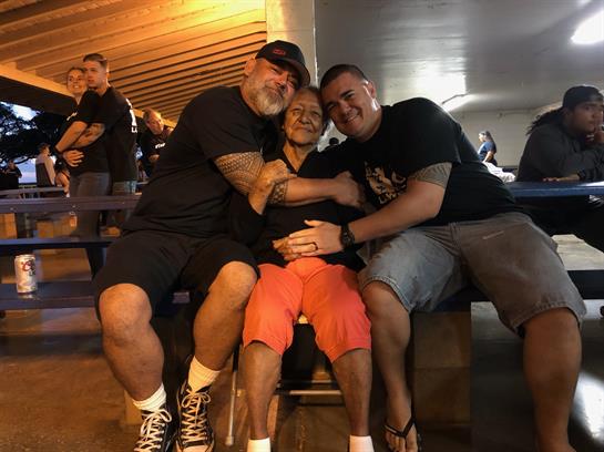 Three friends share a warm moment while sitting together at a lively outdoor event.