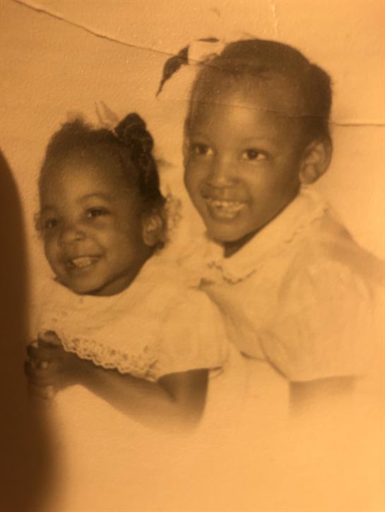 Sisters enjoy a playful moment together, displaying happiness and warmth in a cozy home environment.