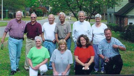 A diverse group of friends poses together outdoors, smiling and enjoying each other's company.