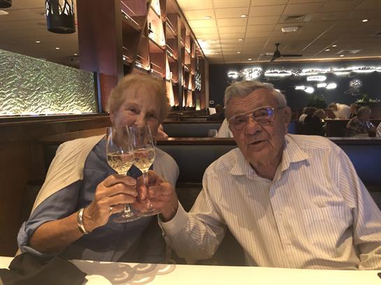 A joyful couple enjoys a special moment in a restaurant, glasses raised in celebration.