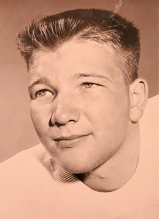 A young man smiling confidently with a classic hairstyle and warm expression, radiating joy.